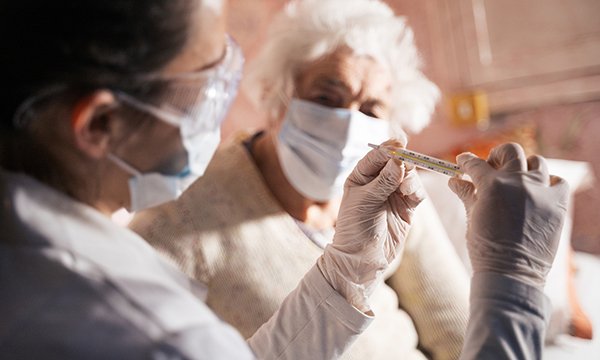 nurse with a care home resident, both wearing face masks during the COVID-19 pandemic