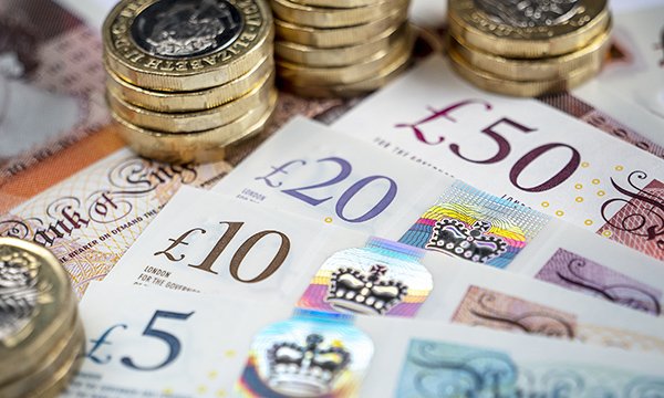 Picture shows piles of £1 coins and assorted UK bank notes.