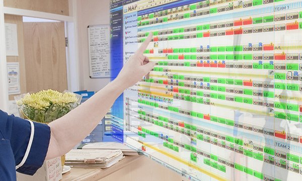 A nurse pointing to a duty roster