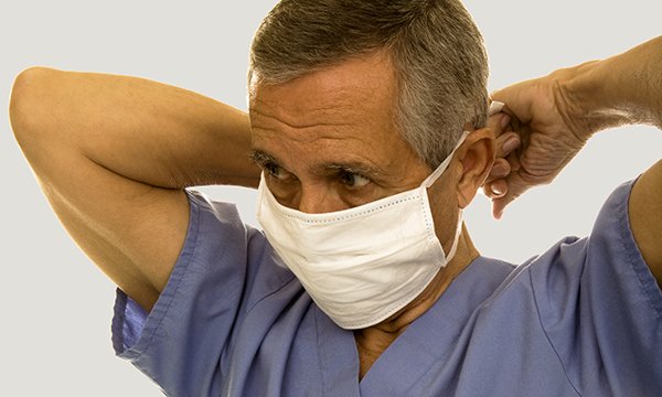 Older nurse dons face mask, as NHS pensioners face return of pension abatement rule