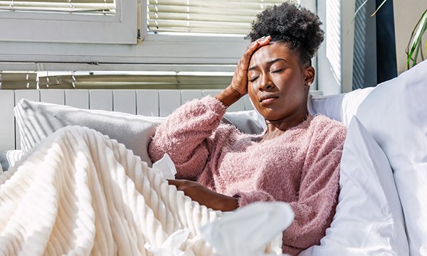 woman looks unwell at home as NHS issues guidance to employers on long-COVID