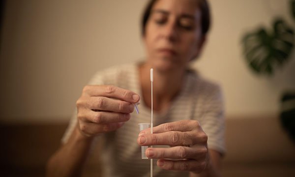 woman takes a lateral flow test as nurses told to continue self-isolating and rules are relaxed for public in England
