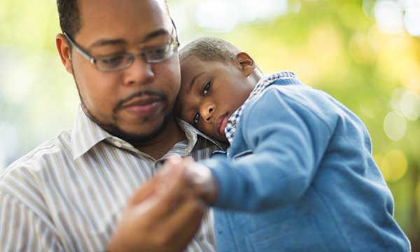 Man looks care-worn as he holds toddler in his arms