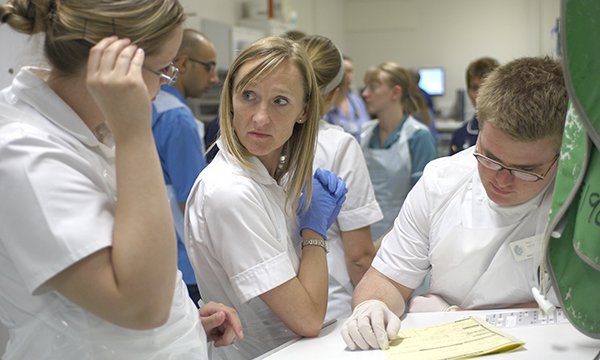 Nursing staffing gather round to confer and look at notes