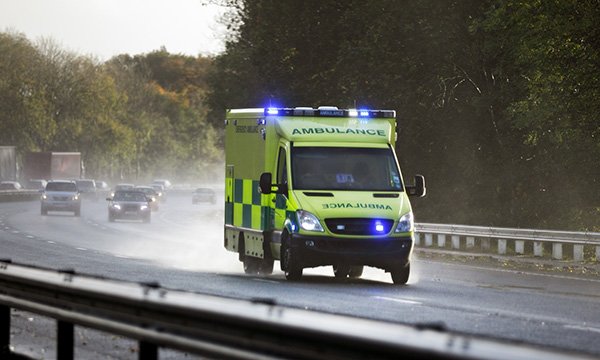 An ambulance with lights flashing on a busy road