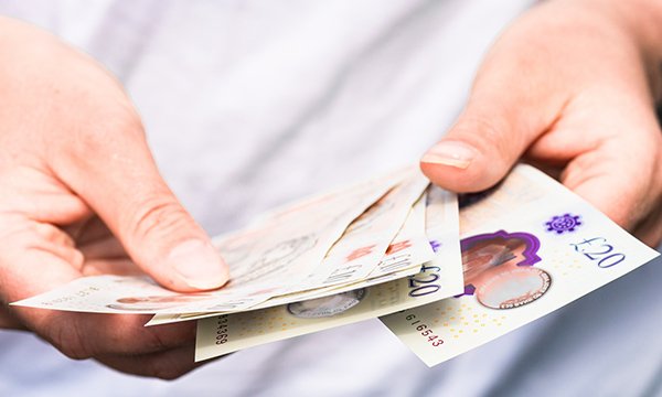 Photo of someone counting £10 and £20 notes in their wallet: the NMC has frozen its registration fee to £120 for another year