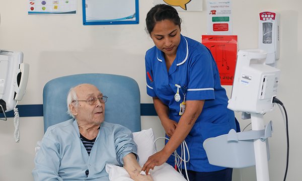 Photo of overseas nurse with patient, illustrating story about rise in overseas recruits