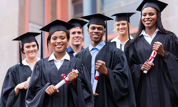 Young graduates standing in front of university building on graduation day