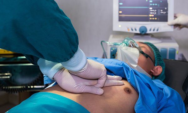 A healthcare professional carrying out cardiopulmonary resuscitation on a male patient