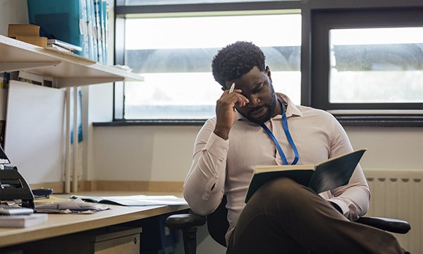 Man in civvies, wearing blue lanyard, sits in consultation room looking downcast