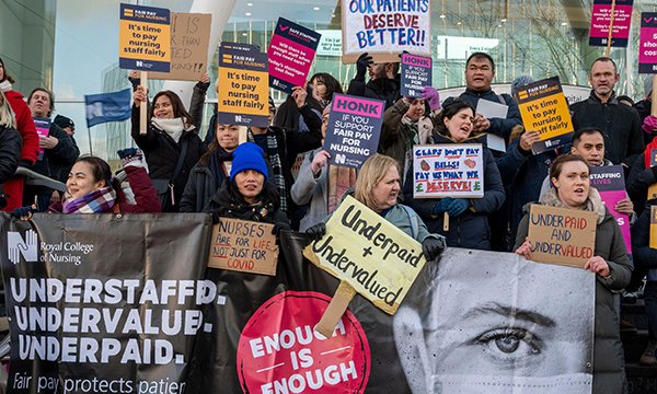 Striking nurses on a picket line holding placards