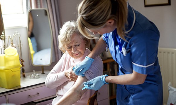 Photo of district nurse caring for a patient in their home, illustrating a story about a fall in district nursing student numbers