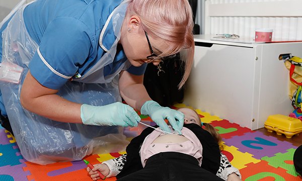 A girl is cared for by a nurse in her own home, as part of hospital at home services