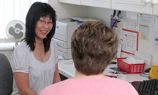 General practice nurse smiles as she consults patient – GPNs are to get 6% pay rise soon