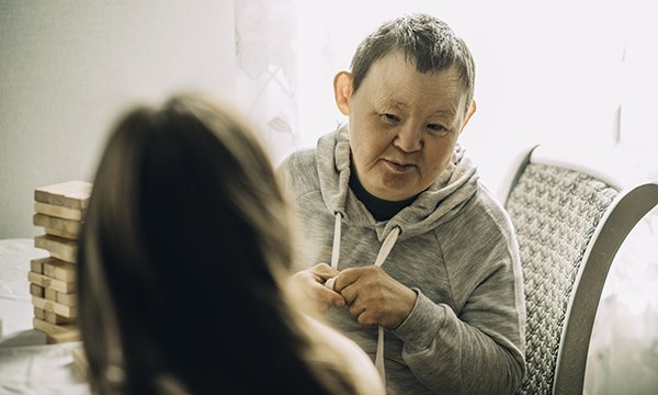 A man with learning disabilities listens carefully to a nurse who has her back to the camera