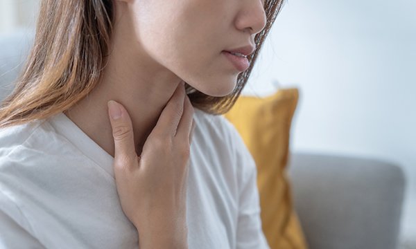 A woman touches her throat/neck area after potentially experiencing non-fatal strangulation