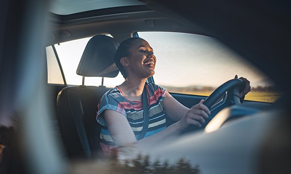 A happy woman at the wheel of a car singing along to music