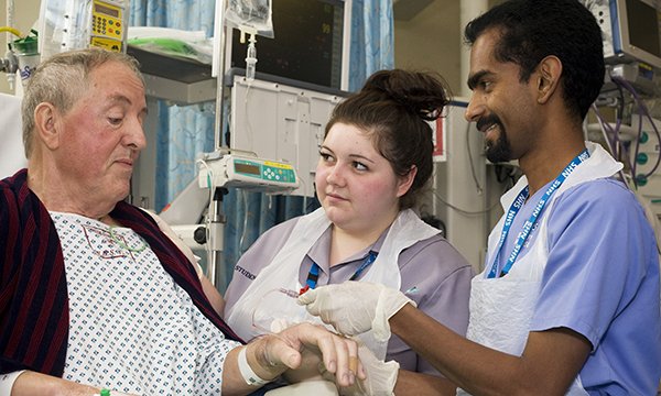 Photo of nursing students with a patient, illustrating a story about cutting length of nursing degrees