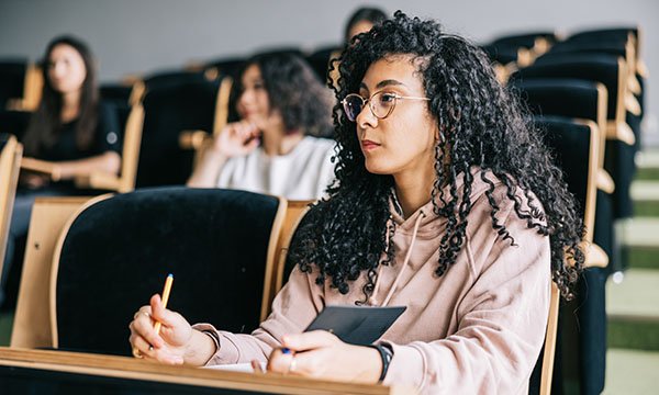 A student sits in a lecture theatre taking notes