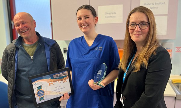 Brendon Clancy standing next to Alice Chappell who is holding an award that has been presented to her by Kirsty Williams