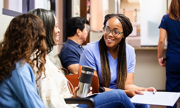 A triage nurse speaks to a patient and her friend to assess their symptoms in the emergency department
