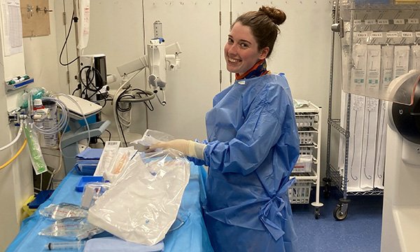 Article author and newly registered nurse Alice Amil smiles as she arranges equipment in the cath lab