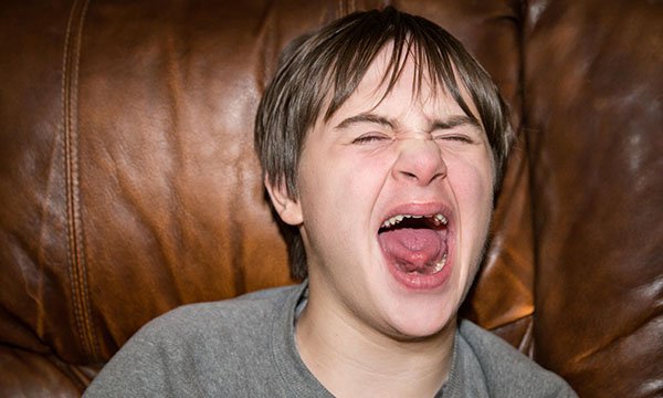 A teenage boy screaming: screaming is among the behaviours that challenge in adults or children with learning disabilities and/or autism