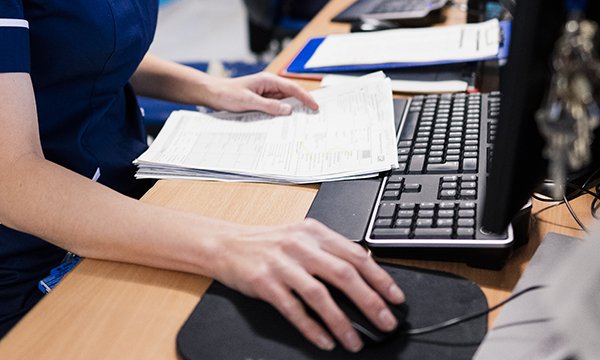 Photo of nurse entering records onto computer 
