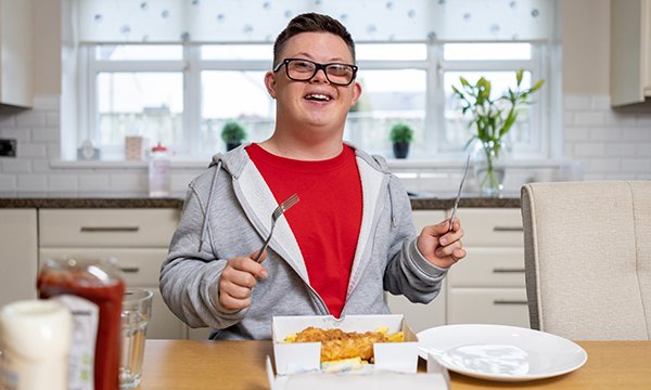 A young man smiling as he gets ready to eat a meal of fish and chips