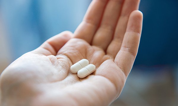 Cupped hand holds two tablets, illustrating case of nurse suspended after stealing paracetamol from ward