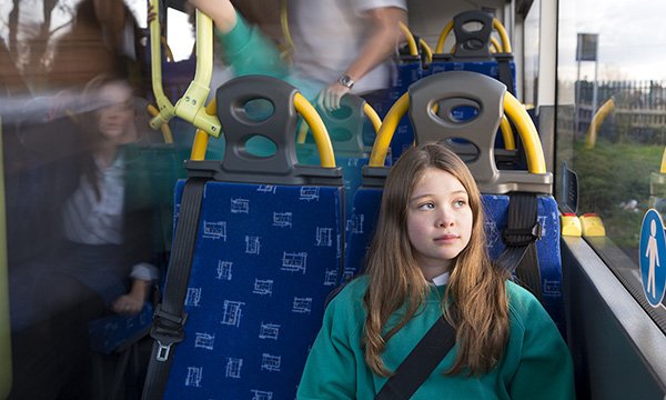 A girl on a bus seems pensive as she looks out of the window