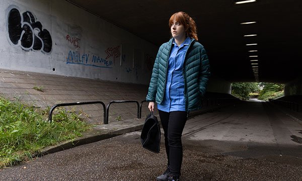 A community nurse looks apprehensive as she emerges into the daylight from a long, dark pedestrian tunnel 