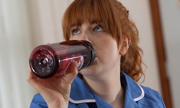 Picture shows a nursing student in uniform sipping from their own refillable water bottle during a shift