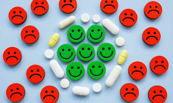 Applying the principles of recovery to the management of psychotropic medications such as antidepressants can generate passionate debate. Illustration shows unhappy faces on the outside of a circle of antidepressants which has an inner circle of smiling f