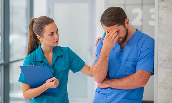Traumatic events can have a huge effect on nurses in emergency departments and healthcare staff often need space and time to reflect. Picture shows a nurse with his head in his hand leaning against a wall, while a colleague offers support