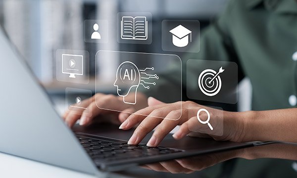 Using AI for nursing degree: a person’s hands typing on a laptop computer, with illustrated icons representing study and technology hovering above them on the image