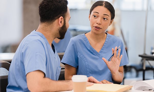 Nurse reflecting on an error: a nurse raises her hand in a gesture of explanation during a conversation with a colleague