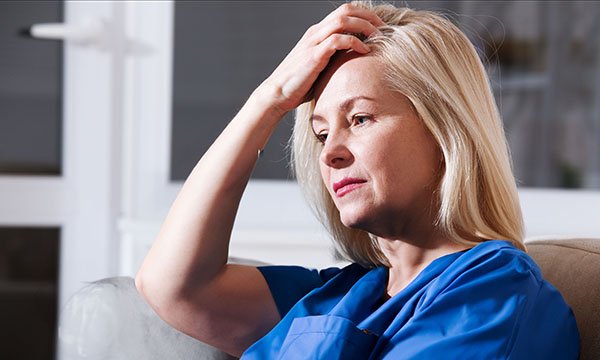 Nursing during menopause: nurse sits down after a shift, appearing anxious