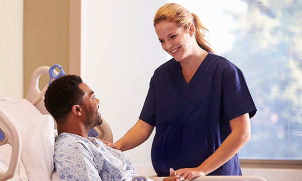 A pregnant nurse at a patient’s bedside