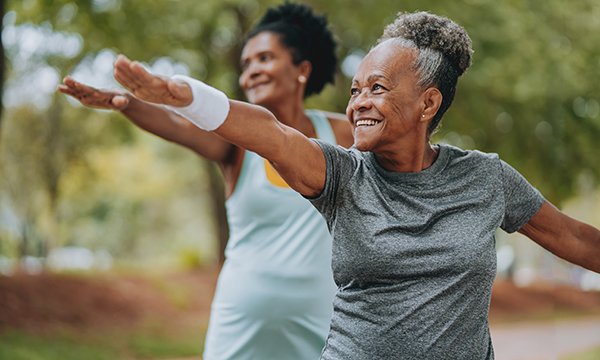 wo older women doing stretch exercises in a park. A study found that nursing home residents who did not engage in physical activities had a five-fold increased risk of declining mobility