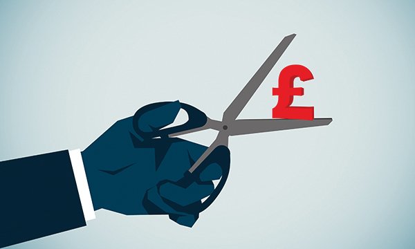 Nursing bank shift pay cuts: illustration showing a hand holding a pair of scissors as the person starts to cut into a red UK pound sign
