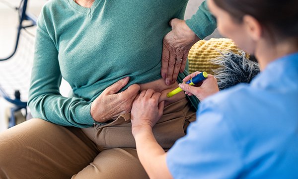 Diabetes insulin regimens: a community nurse administers insulin to a patient on a home visit
