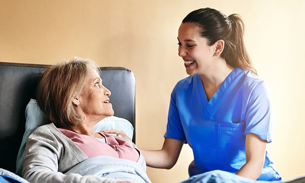 End of life care nursing career options: cheerful nurse at patient's bedside