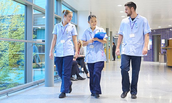Foot health for nurses: three nurses walk in a hospital corridor