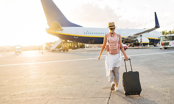Taking a holiday while signed off sick: a woman walks towards an aeroplane wheeling a suitcase