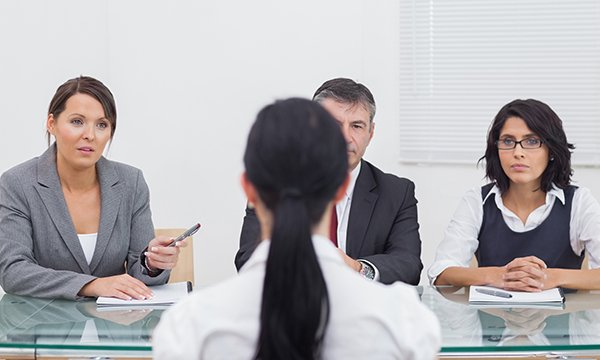 Nurse witness at employment tribunal: woman viewed from behind faces three panellists in official surroundings