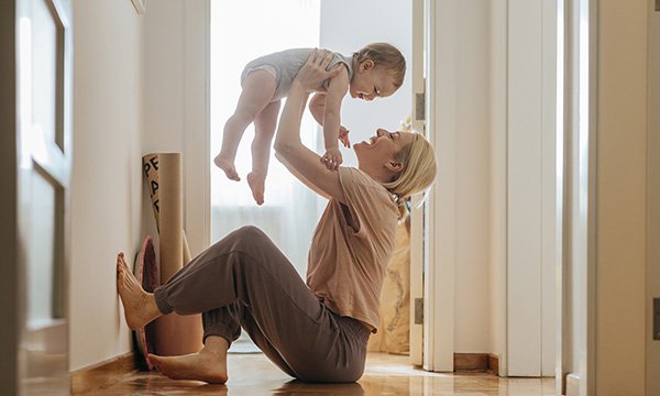 Return to work after maternity leave: a woman sits on the floor at home happily engaging with her young child