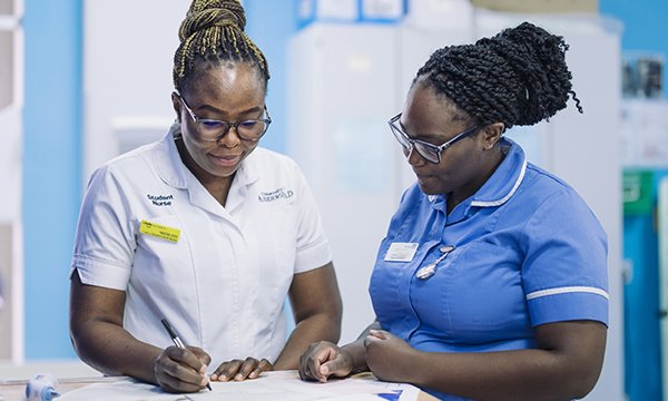 Success as a nursing student: a nursing student on clinical placement is supervised by a nurse while she completes paperwork on a ward