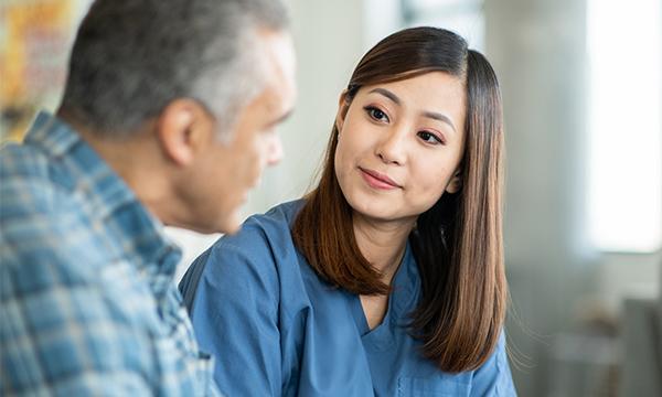 Active listening in nursing: nurse sitting with a service user, making eye contact as he talks