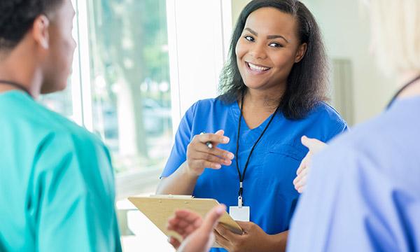 Relational leadership: a senior nurse smiles while talking warmly with two team members